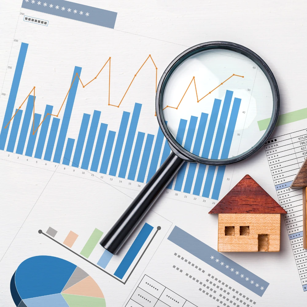 Diagramme, Lupe und Miniaturhaus als Symbol für Immobilienbewertung